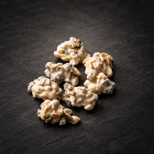 Ambachtelijke pindarotsjes met witte chocolade op een donkere leisteenachtergrond