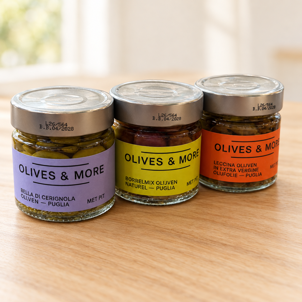 Drie potten Olives & More olijven: Bella di Cerignola, borrelmix en Leccina op een lichte houten ondergrond